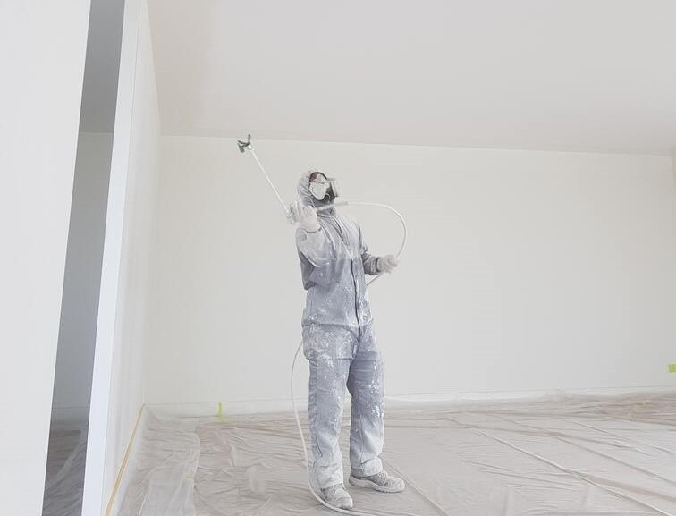 Vakman die latex spuit in een woonkamer