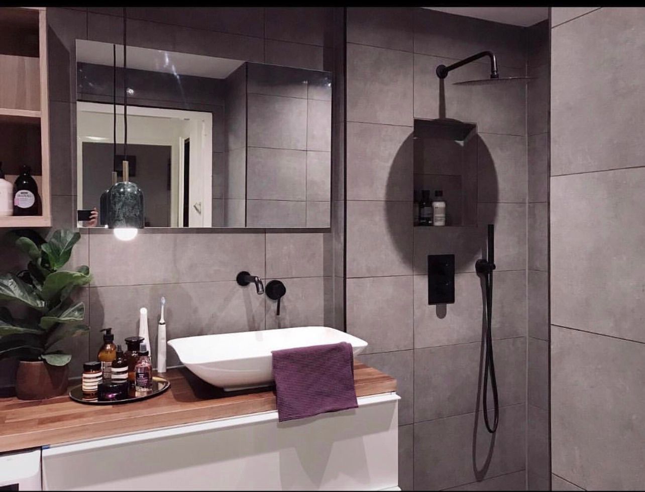 Gerenoveerde badkamer met donker tegelwerk en ligbad